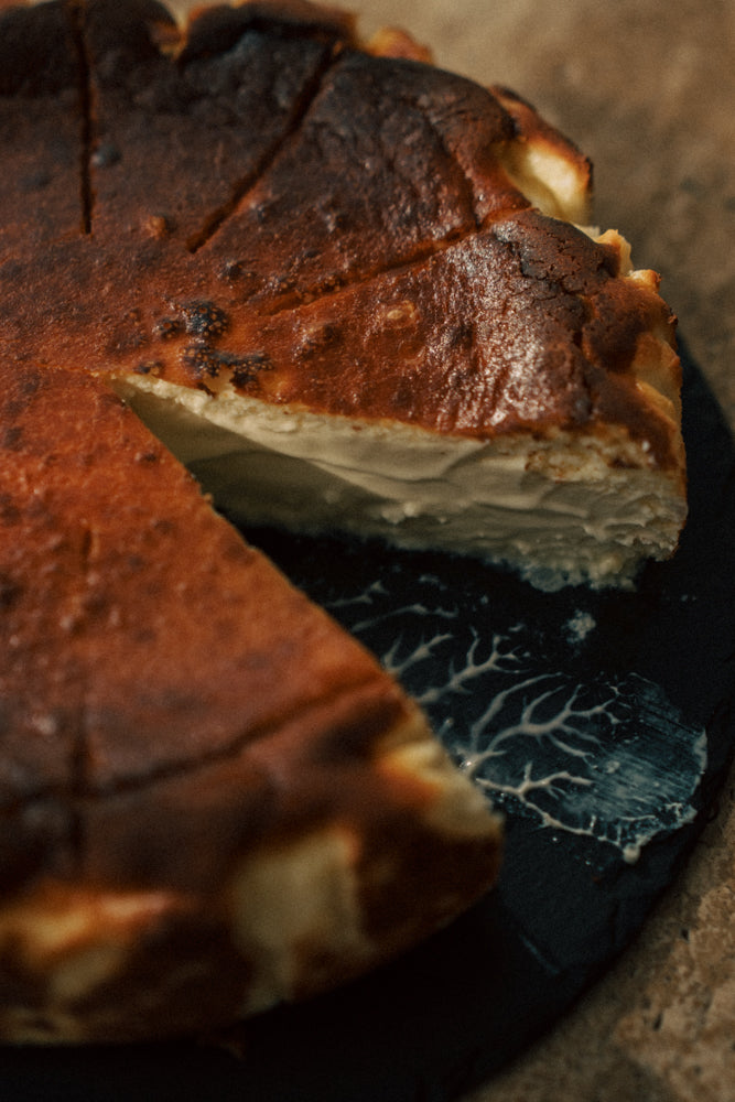 Close-up of a baked dessert with a slice removed on a dark surface