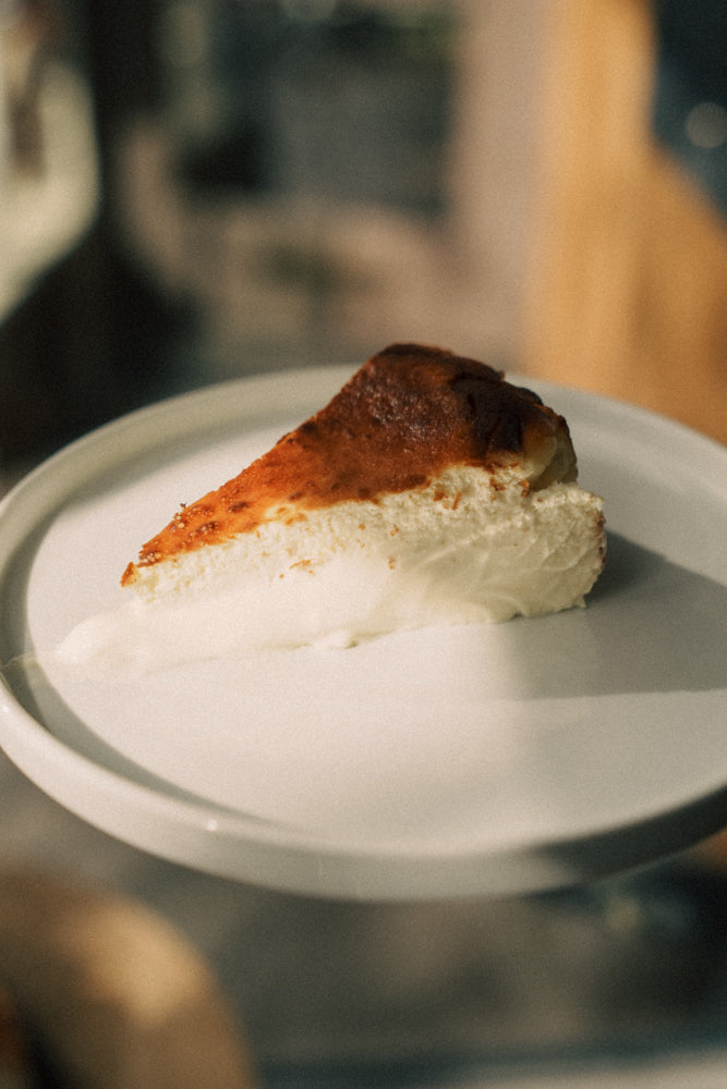 Slice of cheesecake with a graham cracker crust on a white plate.
