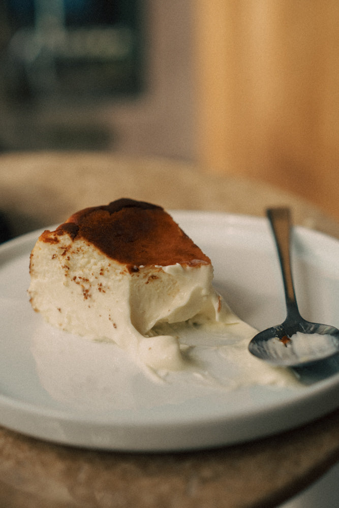 Slice of cheesecake on a plate with a spoon, blurred background